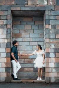 A couple holding hands in front of a brick wall